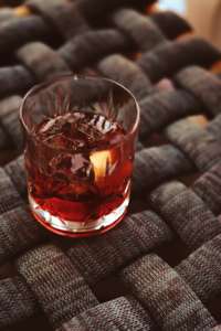 A Negroni cocktail is pictured on a woven table top
